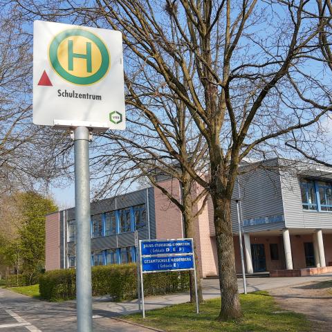 Bus-Halte-Stellen-Schild vor Schul-Gebäude