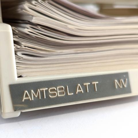 Ablagekorb mit Blättern und Schriftzug Amtsblatt NV