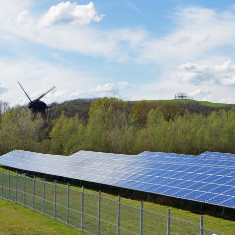 Solarmodule in Landschaft mit Mühle und Hallenhaus im Hintergrund