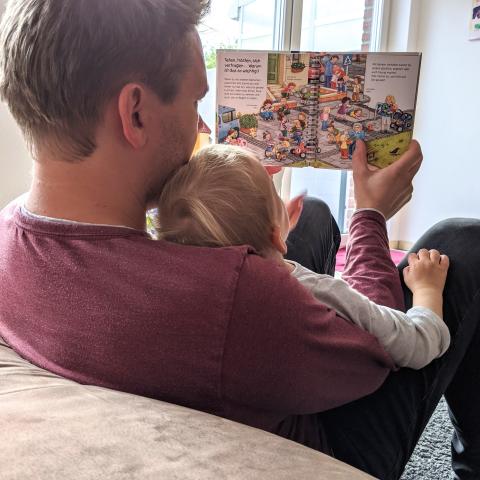 Mann liest Buch mit Kind