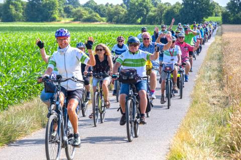 Radelnde fahren an Feldern vorbei