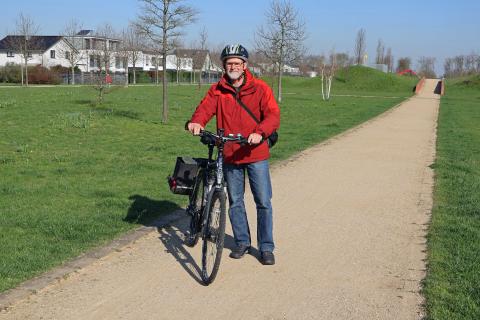 Mann mit Fahrrad vor Wiese