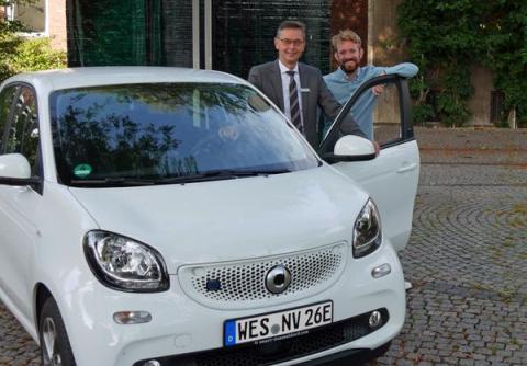 Bürgermeister und Klimaschutzmanager vor E-Auto