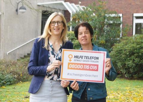 Zwei Frauen mit Schild Hilfetelefon