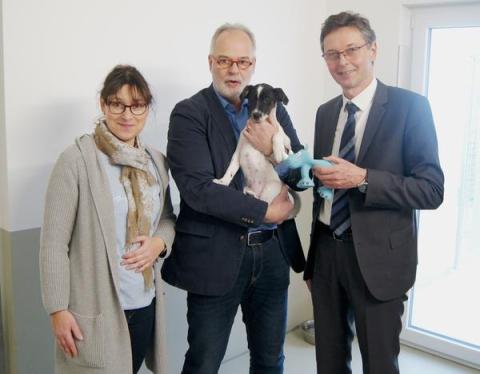 1 Frau und 2 Männer, einer davon mit kleinem Hund auf dem Arm