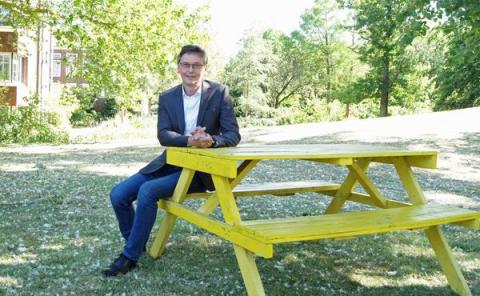 Bürgermeister sitzt auf Picknickbank vor Rathaus