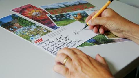 Postkarten und Hand mit Stift