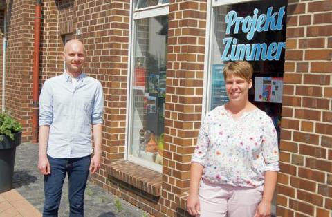 1 Mann und 1 Frau vor Fenster mit Schriftzug Projektzimmer