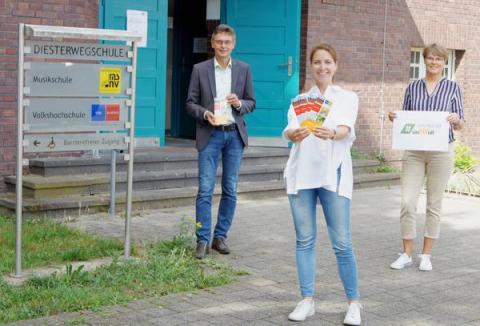 3 Menschen neben Schild