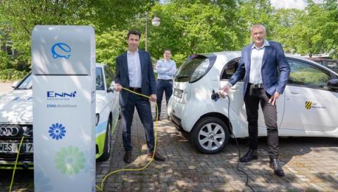 3 Männer mit 2 Autos an E-Ladesäule