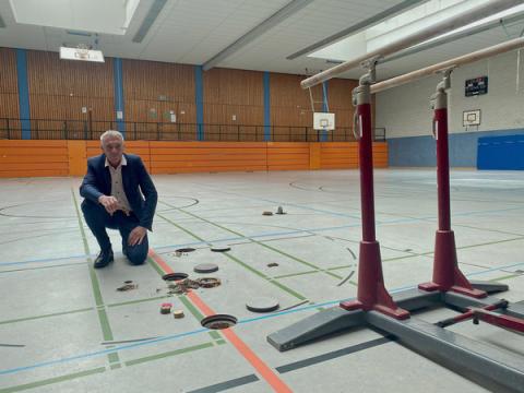 Mann kniet in Sporthalle