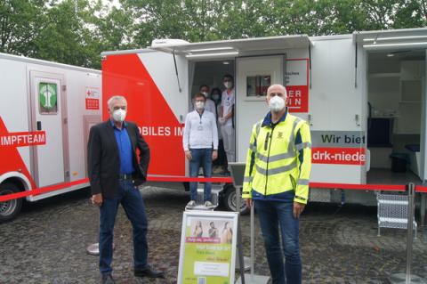 Personen stehen vor mobiliem Impfwagen