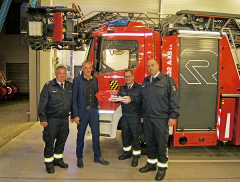Vier Personen vor Drehleiterfahrzeug