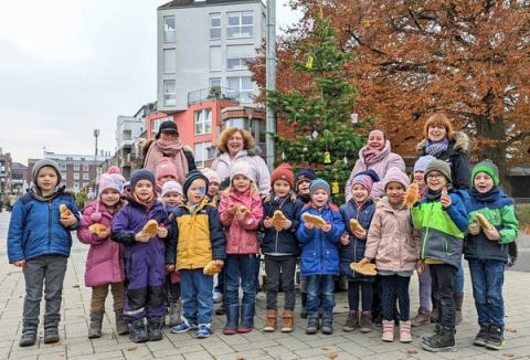 Eine Gruppe Kinder und Erzieherinnen stehen vor Weihnachtsbaum im Freien