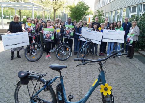 Gruppenfoto mit Schülern und Erwachsenen, im Vordergrund ein Fahrrad