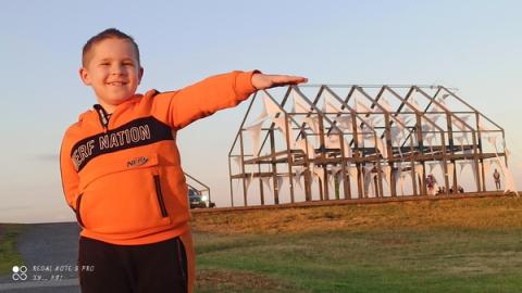 Junge auf Halde Norddeutschland vor Hallenhaus