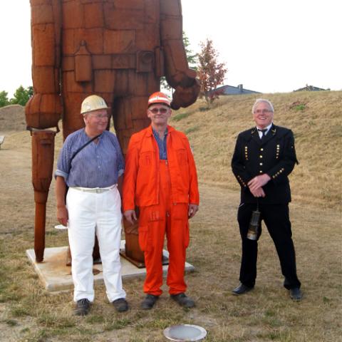 drei Männer stehen vor Bergmannskulptur