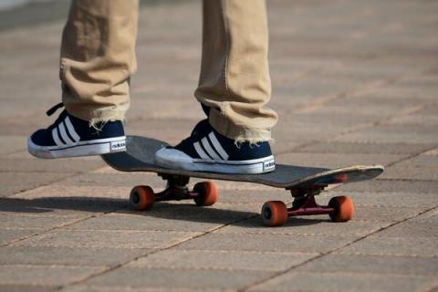 Jugendlicher auf Skateboard, nur Beine und Füße zu sehen