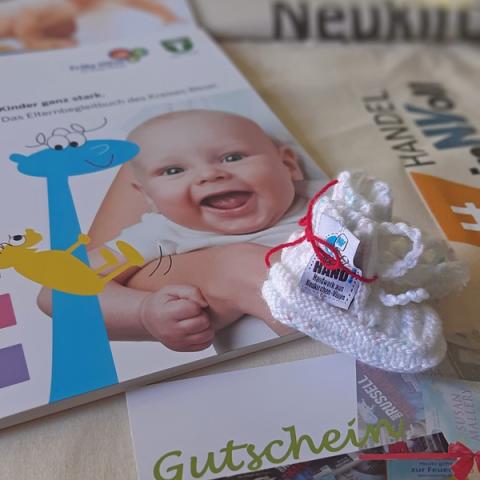 gestrickte Babysöckchen liegen auf Infoprospekten