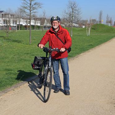 Mann mit Fahrrad vor Wiese