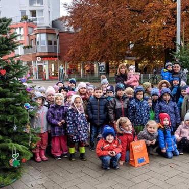 Kindergruppe mit Erziehern vor Weihnachtsbaum draußen Kindergruppe mit Erziehern vor Weihnachtsbaum draußen