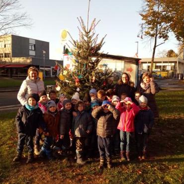 Kindergruppe mit Erziehern vor Weihnachtsbaum draußen Kindergruppe mit Erziehern vor Weihnachtsbaum draußen