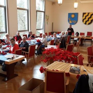 Menschen im Ratssaal basteln Blüten Menschen im Ratssaal basteln Blüten