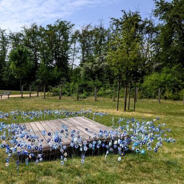 Gestrickte Flachsblüten auf Bügel gesteckt rund um ein Holzpodest Gestrickte Flachsblüten auf Bügel gesteckt rund um ein Holzpodest