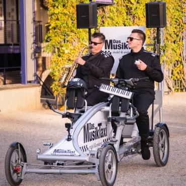 Zwei Männer mit Instrumenten auf umgebautem Fahrrad Zwei Männer mit Instrumenten auf umgebautem Fahrrad