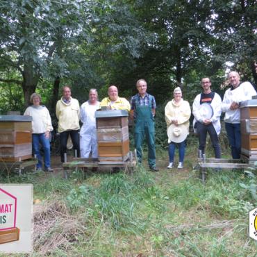 Menschen stehen hinter drei Bienenstöcken Menschen stehen hinter drei Bienenstöcken